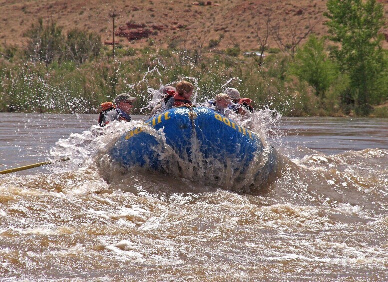 A blue raft with yellow markings being propelled through a river, surrounded by splashing water. 4