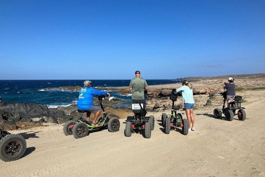 Personas en patinetes eléctricos junto a un litoral rocoso. 2