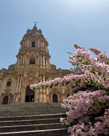 A grand historical building with ornate architecture, including a large dome and columns, and a staircase leading up to its entrance. 1