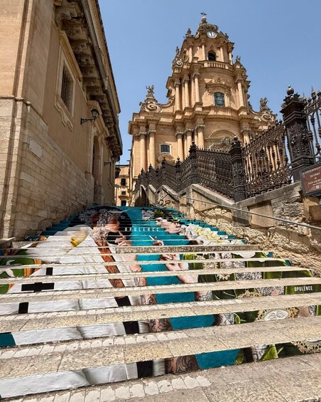 A staircase with colorful steps leading up to a historic building. 4