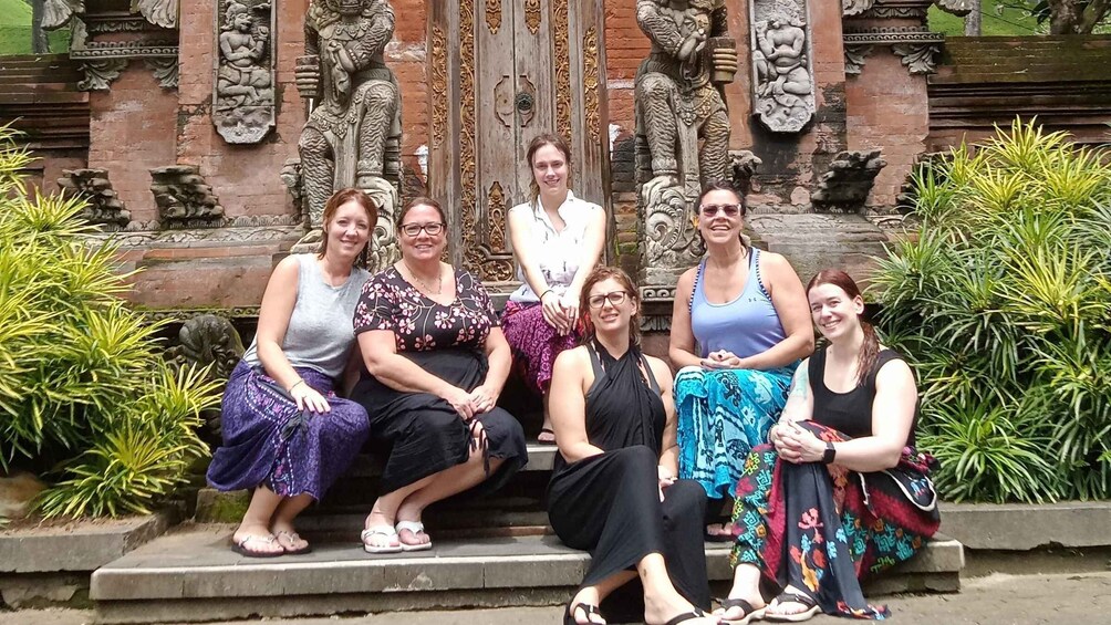 A group of people sitting on steps in front of a temple with intricate carvings. 2
