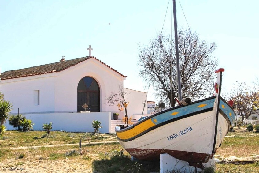 A boat named 'Lhada Culatra' docked near a white building with a red roof. 5