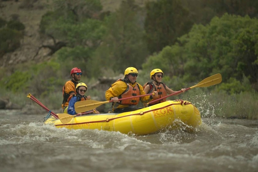 A group of people in a yellow inflatable raft on a river. 2