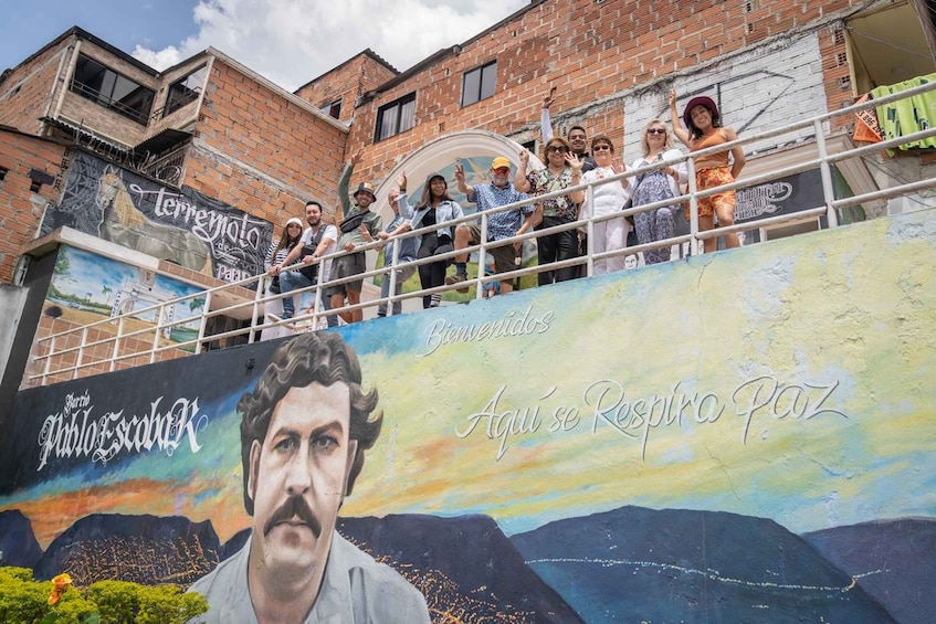 Suuri seinämaalaus, jossa on kuva miehestä ja teksti: ”Barrio Pablo Escobar” ja ”Bienvenidos, aquí se respira paz” (Tervetuloa, täällä vallitsee rauha). 1