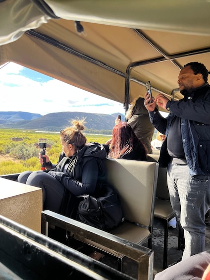 People on a safari vehicle, taking photos of wildlife. 1