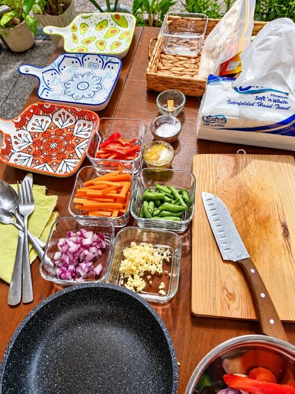 Una mesa con diferentes alimentos, utensilios y una tabla de cortar. 1