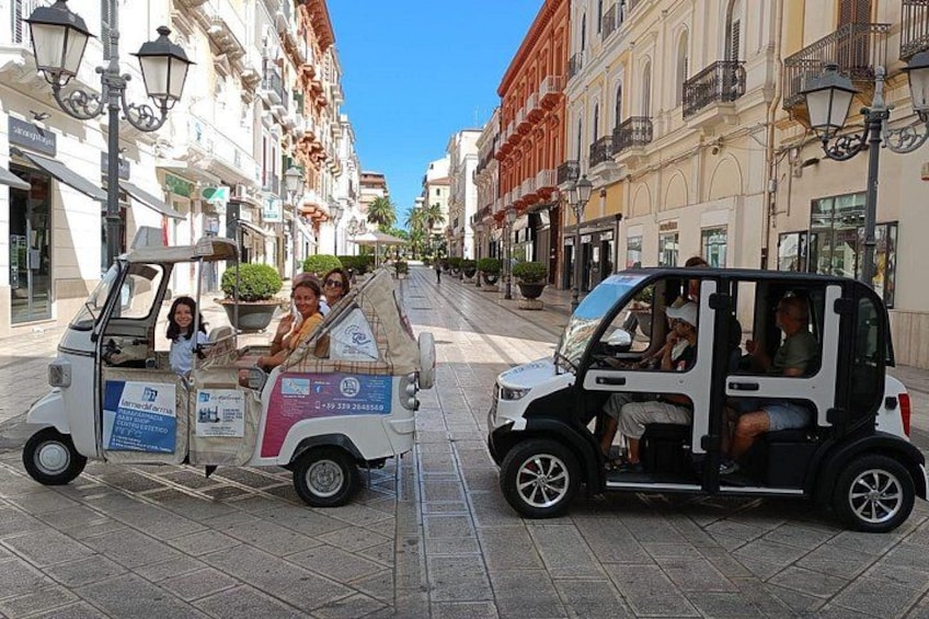A street with parked tuk-tuks and pedestrians. 3