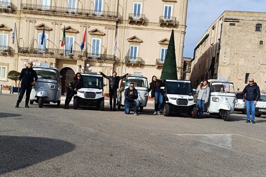 A group of people standing in front of several white vehicles with flags. 4