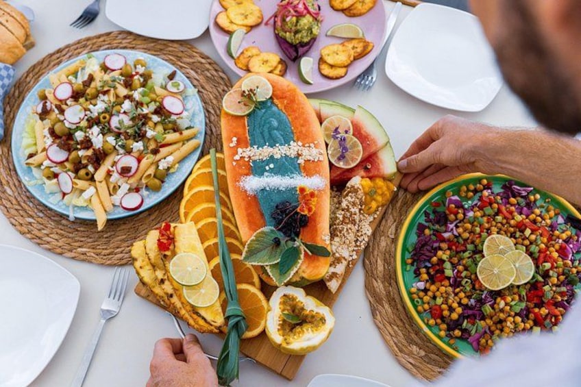 A variety of dishes on a table, including pasta, a carved watermelon, and a colorful salad. 2