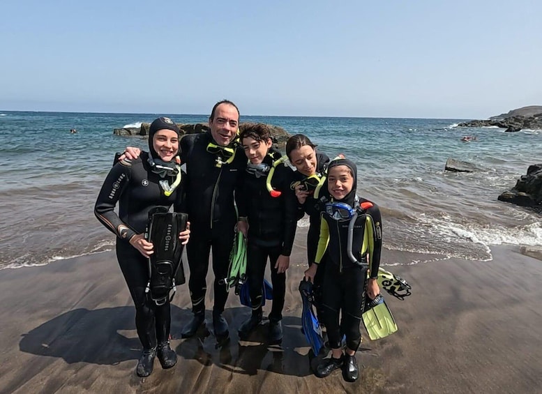 A group of people in scuba diving gear on a beach. 4