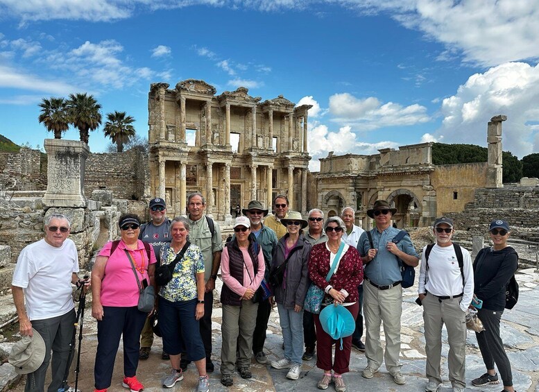 A group of people standing in front of ancient ruins with columns and a stone structure in the background. 3