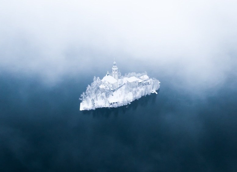 A snow-covered island with a church and buildings, surrounded by fog. 5