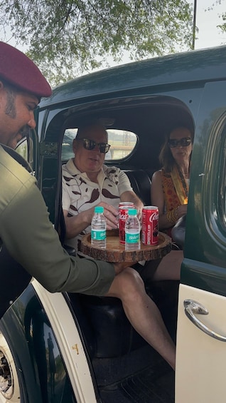 A vintage car interior with three passengers and a table with beverages. 5