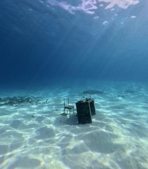 An underwater scene with a chair and a concrete block on the sandy ocean floor. 2