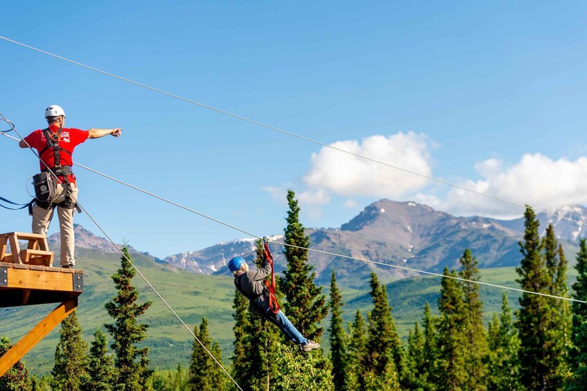 A zip-lining activity with a guide on a platform and a participant mid-air. 3