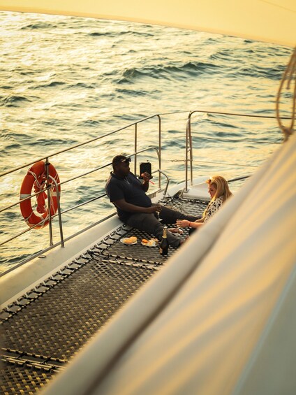 Two people on a boat deck with a lifebuoy and a bottle of champagne. 4
