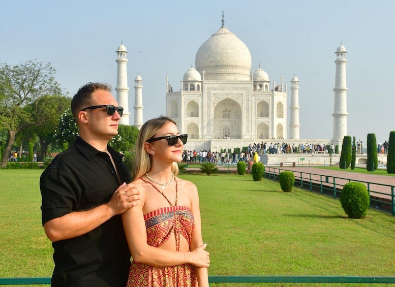 A couple standing in front of the Taj Mahal with the monument in the background. 1