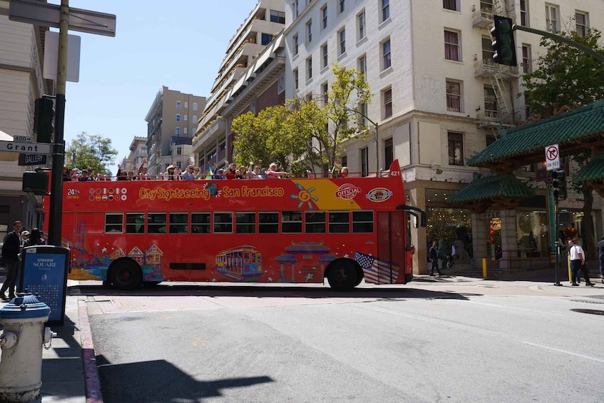 A red double-decker bus with 'City Sightseeing San Francisco' written on it, parked on a city street. 3