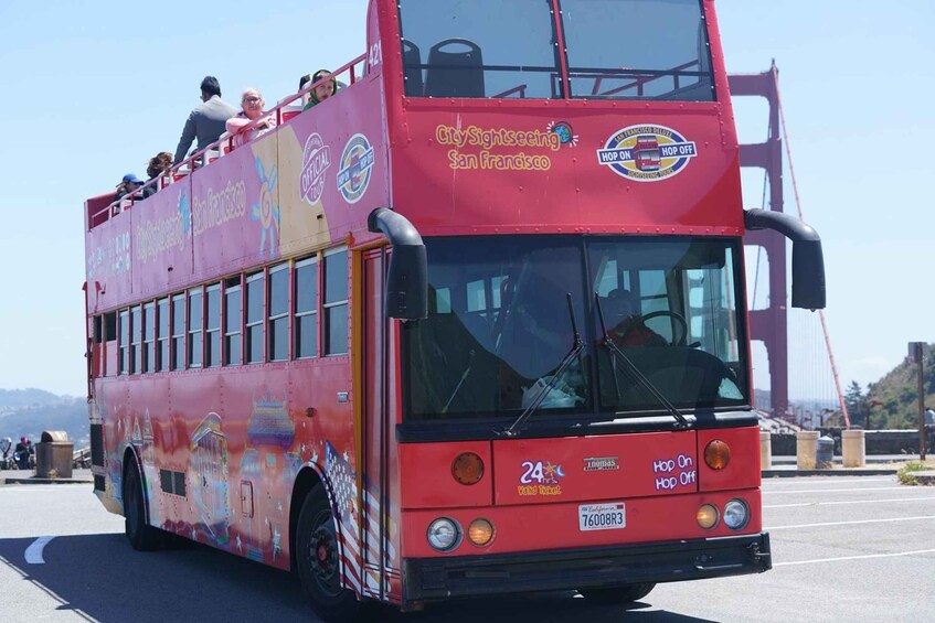 A red double-decker bus with 'CitySightseeing San Francisco' and 'Hop On Hop Off' decals, driving on a road. 4