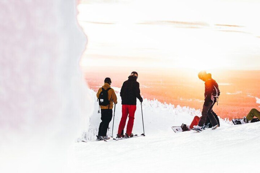 Three people skiing on a snowy slope with a sunset in the background. 3