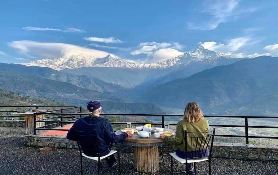 Deux personnes sont assises à une table, avec une vue sur la montagne. 2