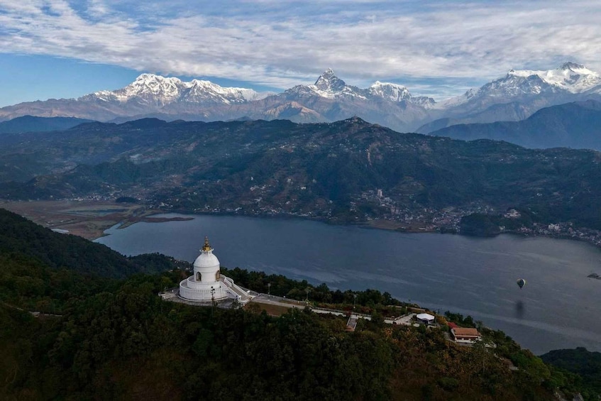 Un bâtiment blanc en forme de dôme, entouré de montagnes et bordé par un lac. 1