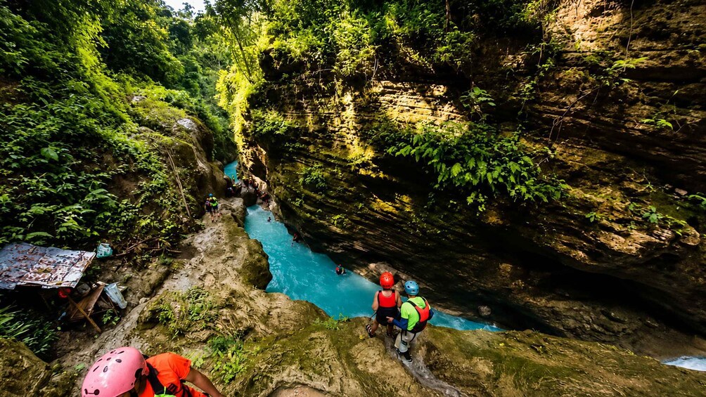 A group of people kayaking in a narrow canyon with lush greenery on the sides. 3