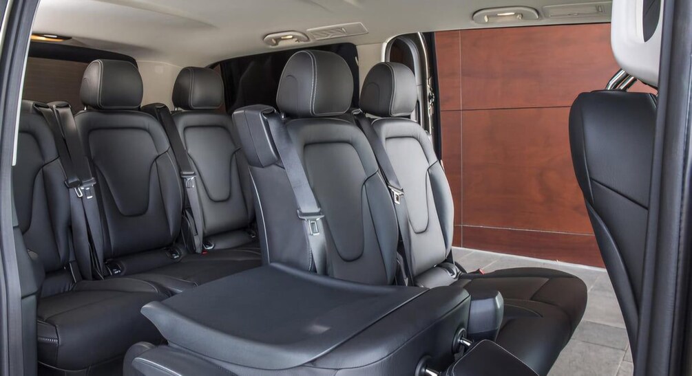 A vehicle interior with black leather seats, a central console, and a wooden panel on the side. 5