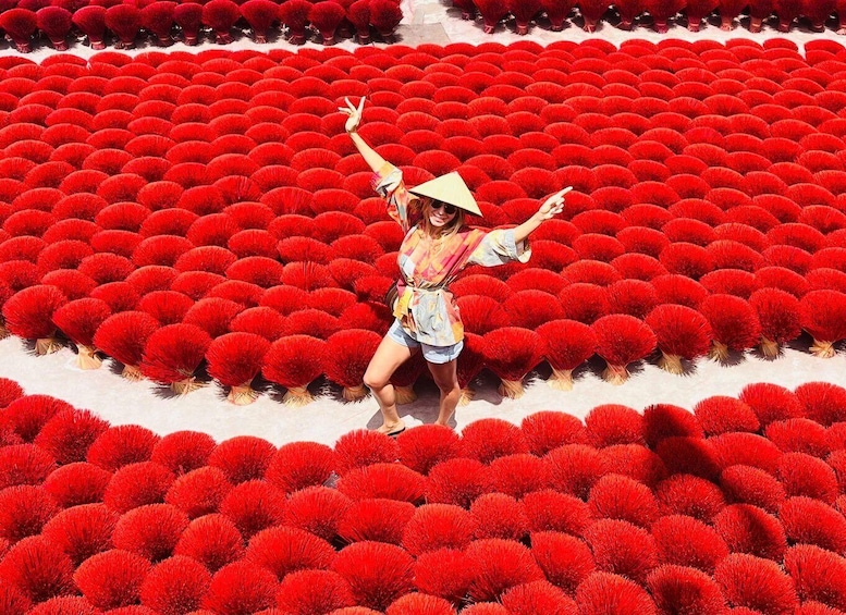 A person standing in a field of red spherical plants. 1