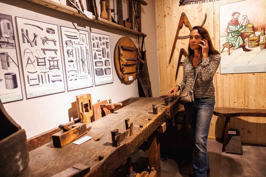 A person in a workshop with tools and wooden objects on a workbench, surrounded by framed diagrams on the wall. 5