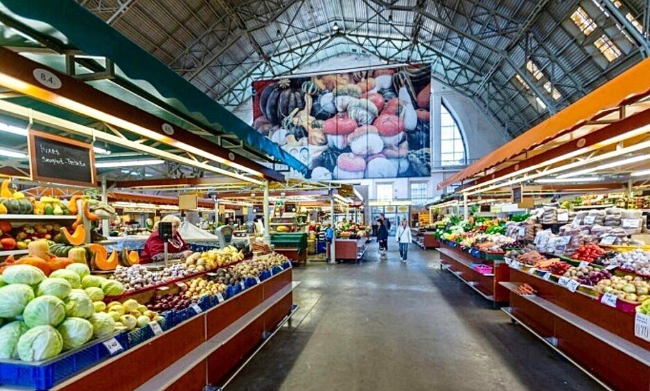 An indoor market with various produce stalls and a large mural on the ceiling. 2