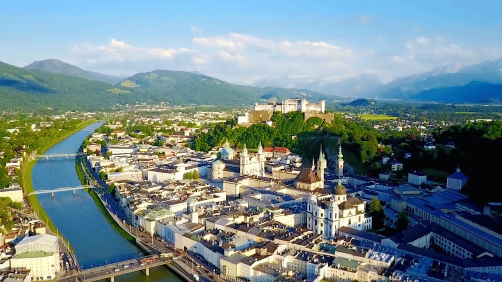 A river flowing through a city with historic buildings and a castle on a hill. 2