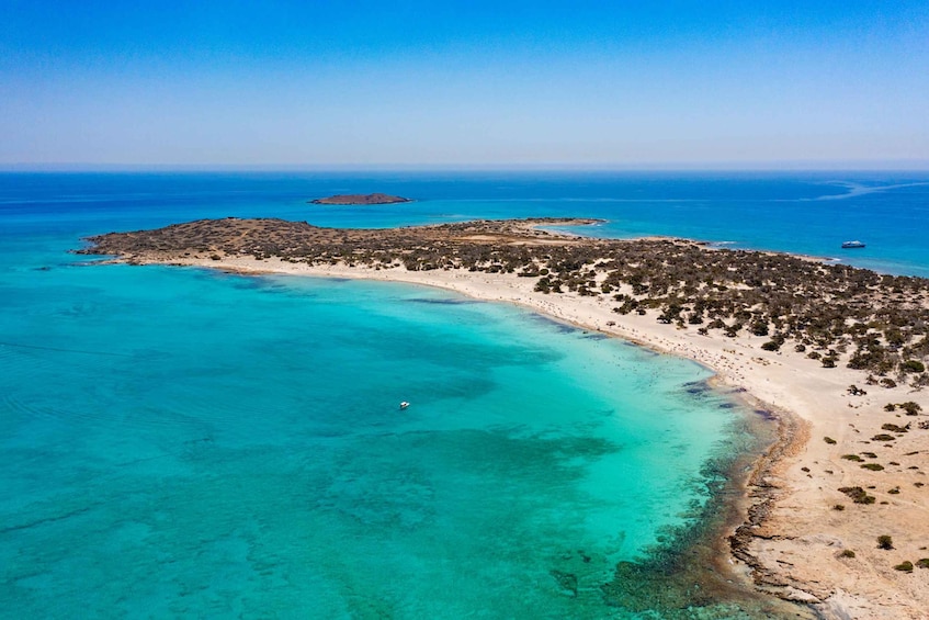 An aerial view of a coastal area with clear turquoise waters, a sandy beach, and a small island in the distance. 1