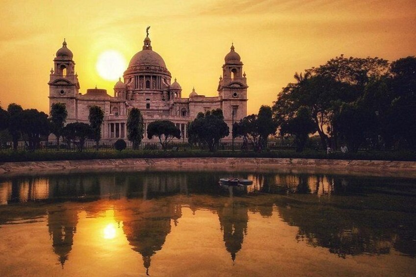 A grand building with domes and towers, reflecting in a calm body of water during sunset. 2