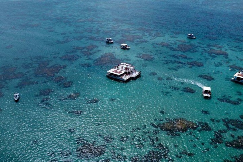 A clear blue sea with a floating structure and several boats. 1