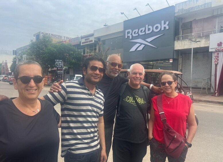 A group of people posing in front of a Reebok store with a street and other shops in the background. 4