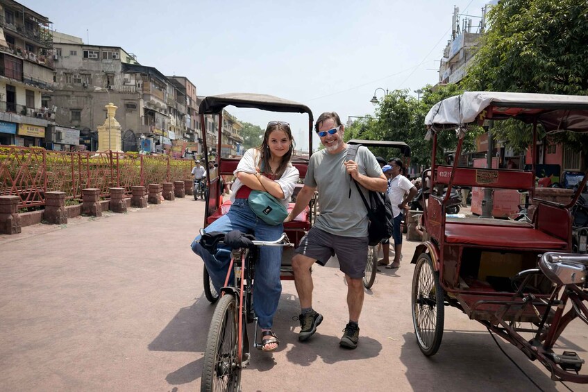 A man and a woman on a bicycle, with a red rickshaw in the background. 3