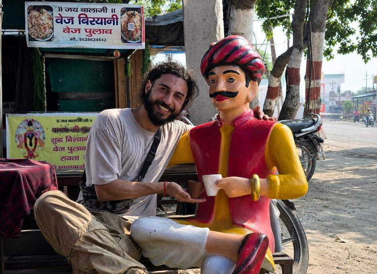 A man sitting next to a colorful statue on a motorcycle. 5