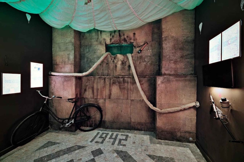 A room with a bicycle, a green container, and a tiled floor marked '1942'. 4