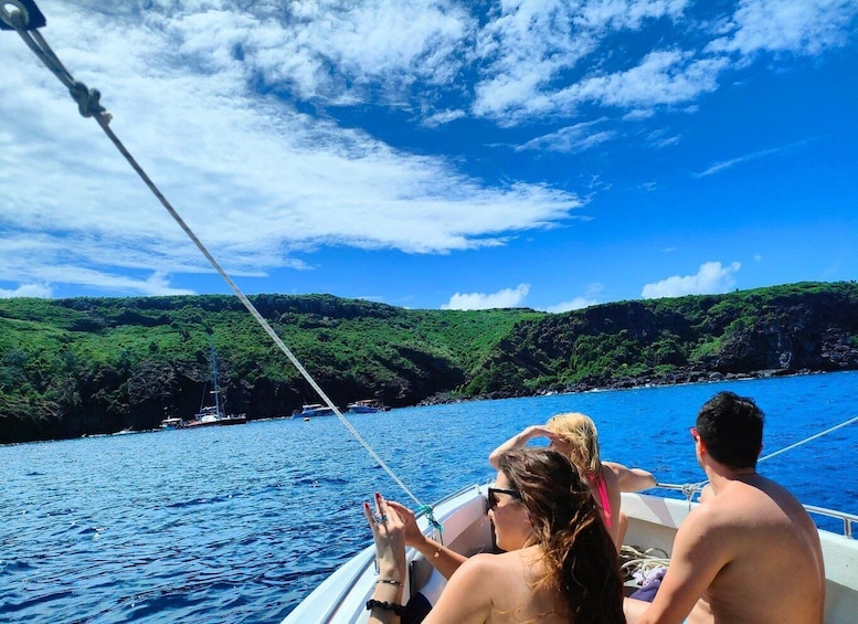 A boat on a clear blue sea with lush green hills in the background. 3