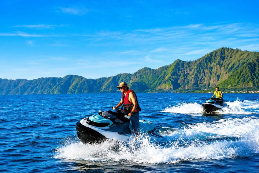 Two people jet-skiing on a lake with mountains in the background. 5