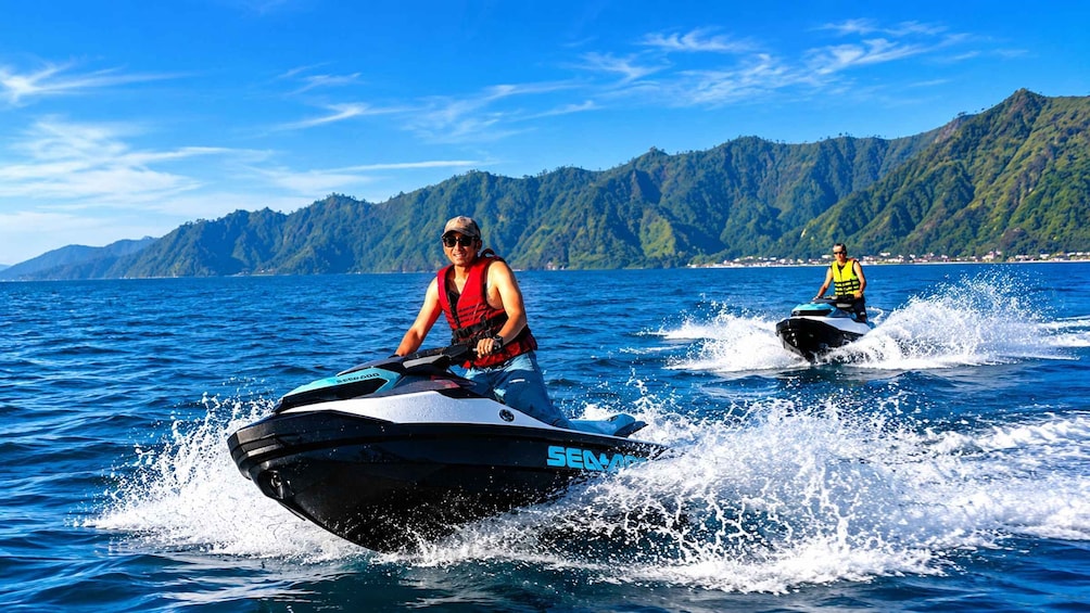 Two people jet-skiing on a lake with mountains in the background. 4