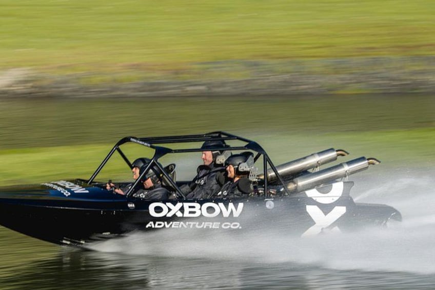 A speedboat with two people, water spray, and the text 'OXBOW ADVENTURE CO.' 2