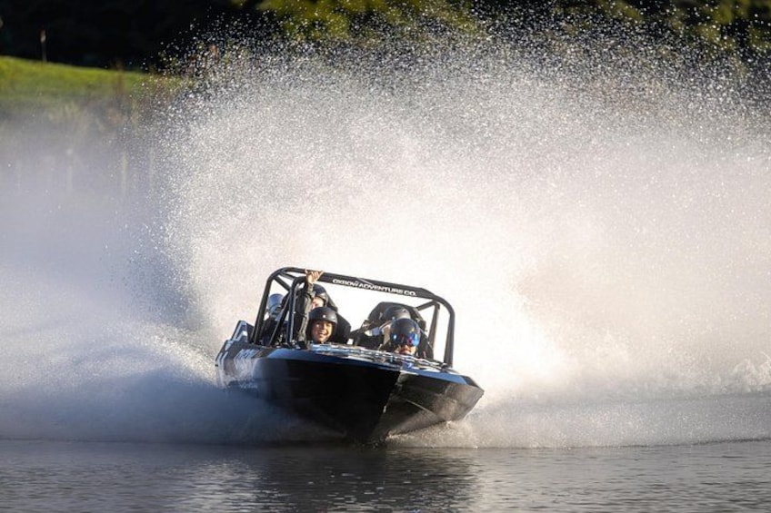 A speedboat creating a large spray of water as it moves across a body of water. 2