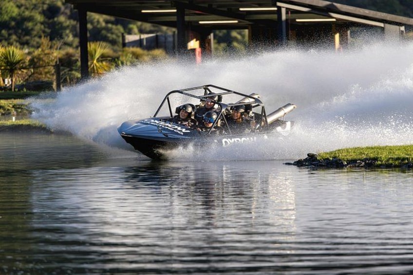A speedboat creating a large wake on a body of water with a bridge in the background. 3