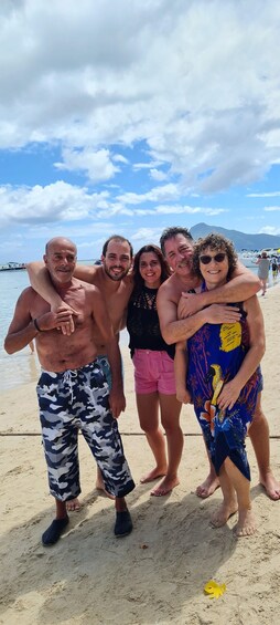 A group of people on a sandy beach with boats in the background. 2