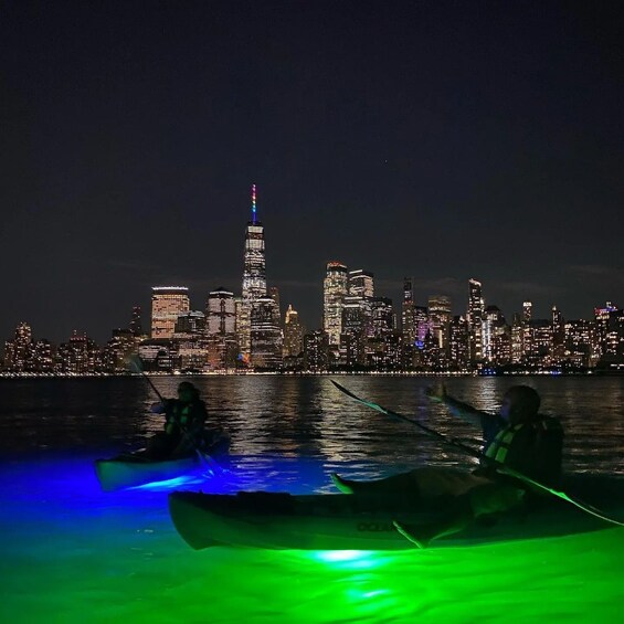 A nighttime city skyline with illuminated buildings across a body of water. 1