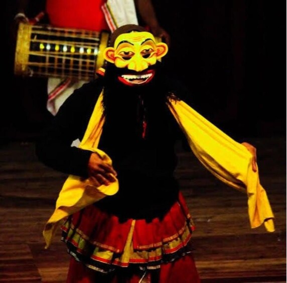 A person in a traditional costume with a mask, holding a yellow cloth. 5