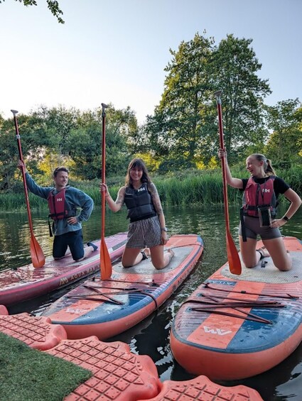 Three people on paddleboards in a calm body of water, surrounded by greenery. 3
