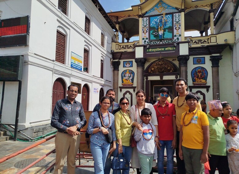 Een groep mensen voor een tempel met traditionele architectuur en religieuze schilderijen. 4